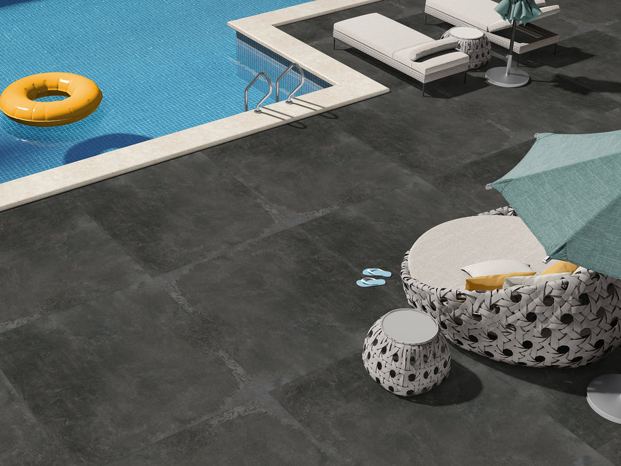 Terrastegel in betonlook met formaat  90x90 cm geplaatst op een terras met een zwembad.