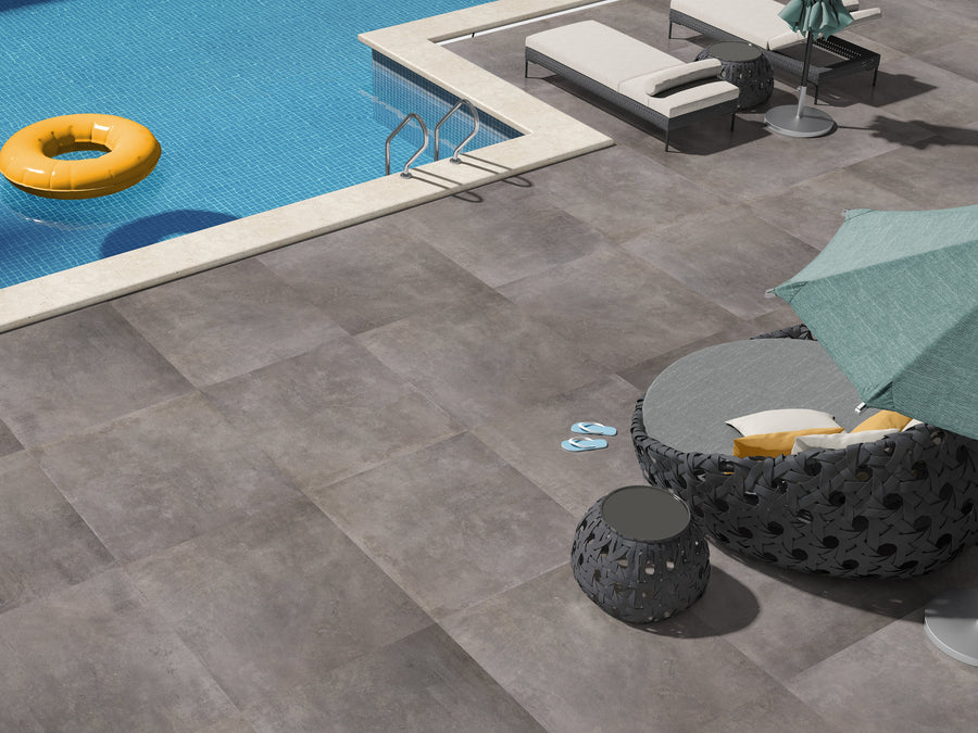 Keramisch betonlook tegel in formaat 80.2x80.2x0.92 cm geplaatst op een terras met een zwembad.